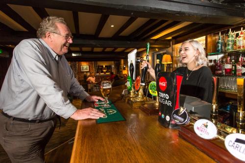 a man and a woman standing at a bar at The Black Swan Inn in Norwich