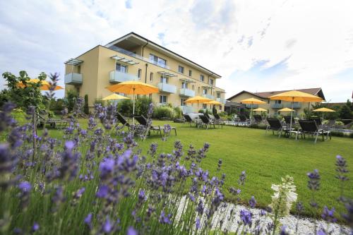 a hotel with a lawn with chairs and umbrellas at Hotel Garni Toscanina - Adults Only in Bad Radkersburg