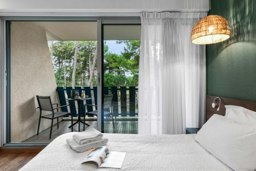 a bedroom with a bed and a view of a patio at Hotel Logis Lacotel in Hossegor