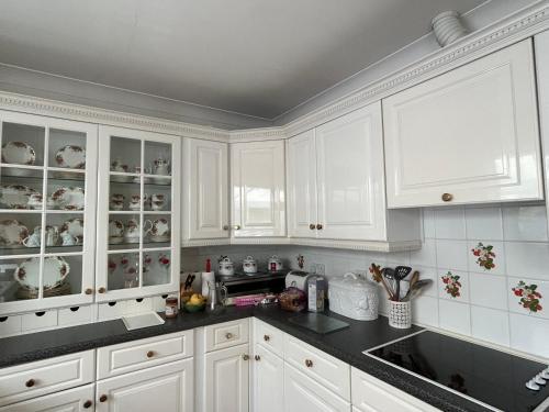 une cuisine avec des armoires blanches et des comptoirs noirs dans l'établissement Curlews, à Feock
