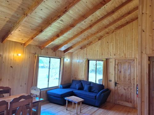 sala de estar con sofá azul en una sala de madera en Cabañas piedra Alta, Huilo Huilo, en Panguipulli
