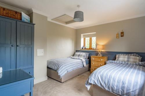 two beds in a bedroom with blue cabinets at Annie's Cottage - Big Skies Holiday Cottages in Sharrington