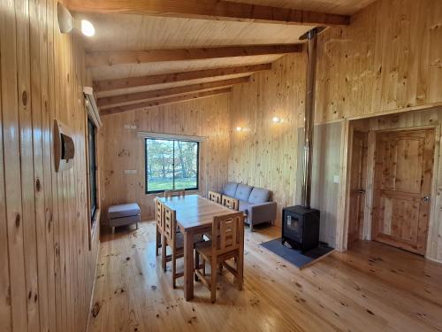 a dining room with a table and chairs and a stove at Cabañas piedra Alta, Huilo Huilo in Panguipulli