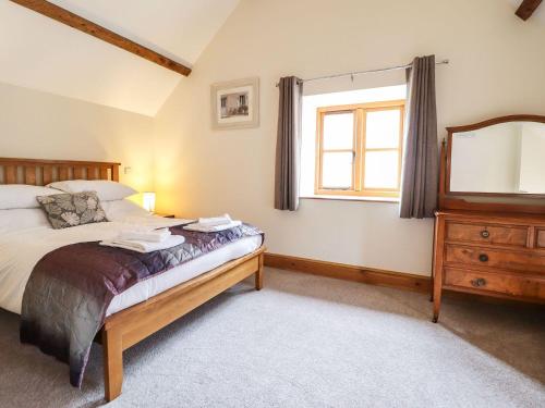 a bedroom with a bed and a dresser and a window at The Barn in Corwen