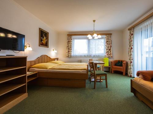 a bedroom with a bed and a table and a chair at Gästehaus Bleiweis-Zehentner in Zell am See