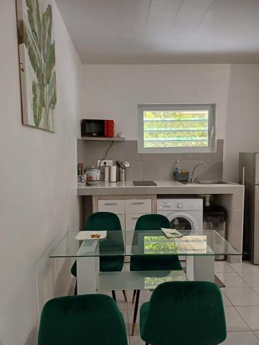 eine Küche mit einem Glastisch und grünen Stühlen in der Unterkunft Résidence DENGUELE in Saint-Laurent du Maroni