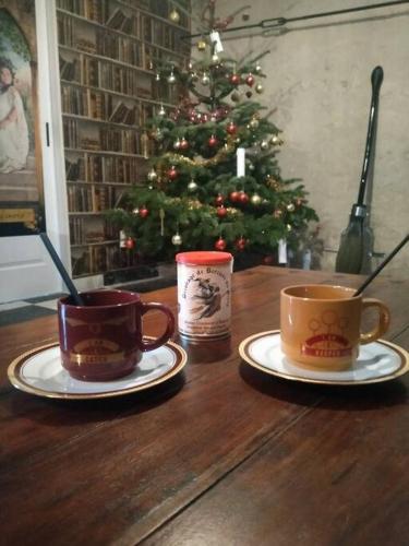 two coffee cups on a wooden table with a christmas tree at Le Petit Gite des sorciers, Chitray, Indre in Chitray