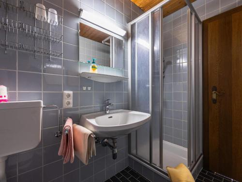 een blauwe betegelde badkamer met een wastafel en een douche bij Gästehaus Bleiweis-Zehentner in Zell am See