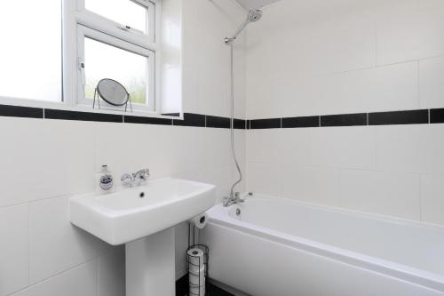 a white bathroom with a sink and a bath tub at 3 Bedroom Home with Private Driveway in Coundon