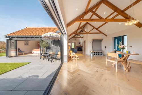 een grote open woonkamer met een houten vloer en een patio bij Large immaculate rural conversion - The Milking Parlour in Ipswich