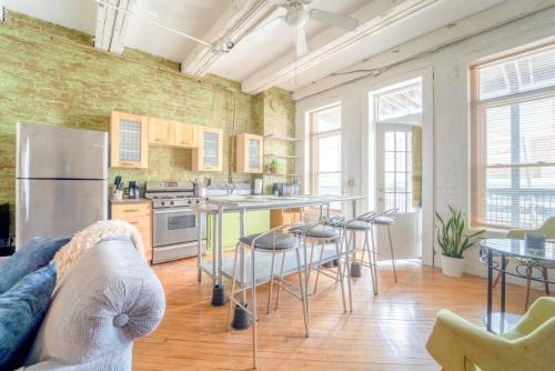 a living room with a kitchen with a refrigerator and tables at Cool Urban Stay Dtwn Apt And Patio in Binghamton