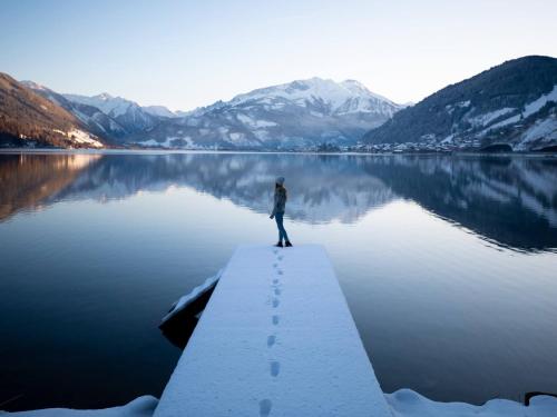 a person standing on a dock over a lake at Gästehaus Bleiweis-Zehentner in Zell am See