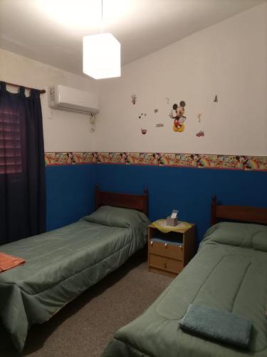 a bedroom with two beds and a blue wall at Casa Norte in La Rioja