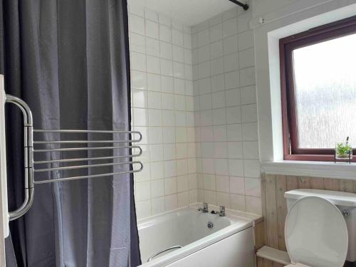 a bathroom with a tub and a shower curtain at Coastal Apartment 2 Bedrooms, Sleeps upto 6, Free Parking in Prestonpans
