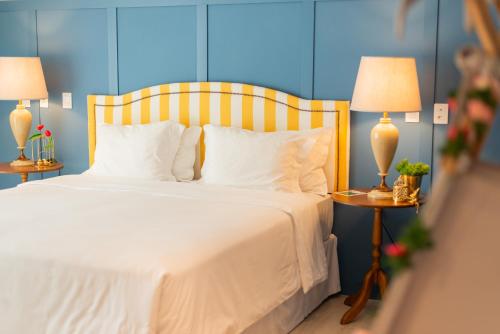 a bedroom with a bed with white sheets and two lamps at Villa do Vale Boutique Hotel in Blumenau