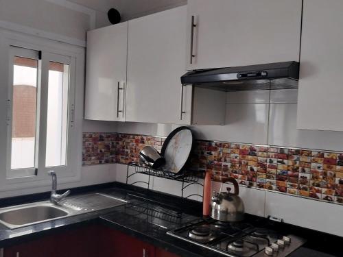 a kitchen with white cabinets and a sink and a stove at Oued laou beach in Oued Laou