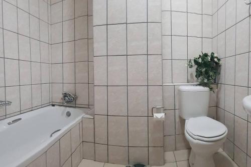 a bathroom with a toilet and a tub and a plant at Dolphin View 20 @ LongBeach in Langstrand