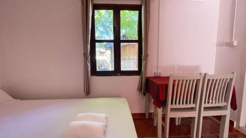 a bedroom with a bed and two chairs and a window at Moukdavan Guesthouse in Luang Prabang