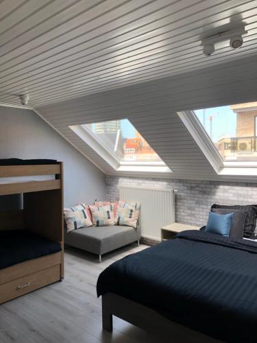 a attic room with a bed and a couch at Enjoyvilla@sea in Ostend