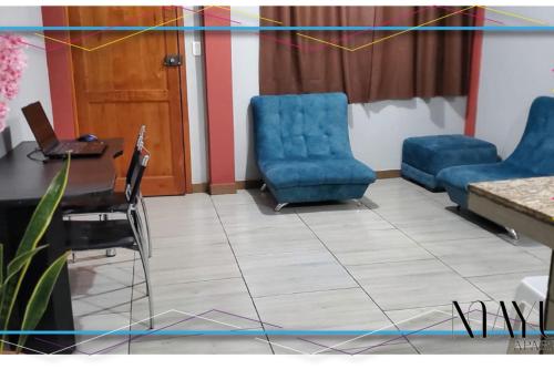 una sala de espera con sillas azules, mesa y ordenador portátil en Departamento en Centro de Tena, en Tena