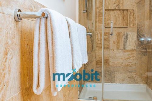 uma casa de banho com um chuveiro e toalhas brancas num toalheiro. em Hermoso y perfecto 2 Hab frente al mar en Cap Cana em Punta Cana