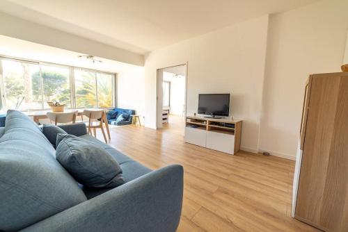 un salon avec un canapé bleu et une télévision dans l'établissement Cadre exceptionnel - Appt Classé 3 entièrement climatisé - Mer-piscine-tennis, à Bandol