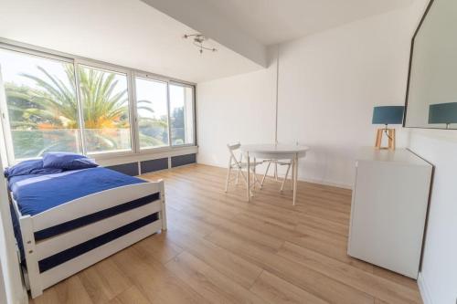 Cet appartement comprend une chambre avec un lit et une table ainsi qu'une cuisine. dans l'établissement Cadre exceptionnel - Appt Classé 3 entièrement climatisé - Mer-piscine-tennis, à Bandol