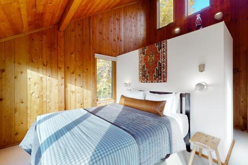 a bedroom with a blue and white bed and wooden walls at Mad River Masterpiece in Irasville