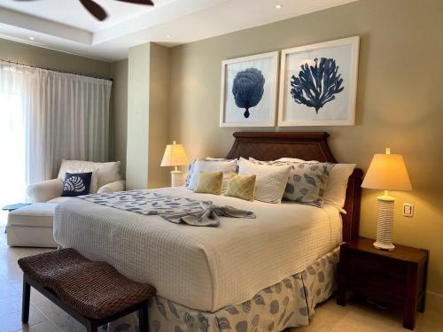 a bedroom with a large bed with two lamps and two posters at Exclusivos apartamentos con vista a la playa en Aquamarina, Cap Cana in Punta Cana