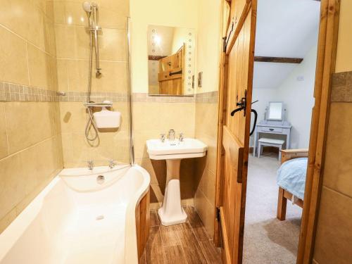 uma casa de banho com uma banheira e um lavatório e uma banheira em Hay Store em Corwen