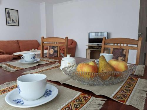 a dining room table with a bowl of fruit and a cup at Lazur Apartment in Burgas