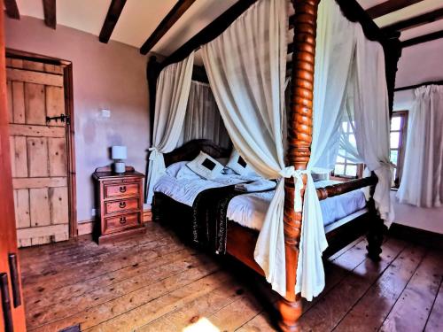 um quarto com uma cama de dossel e piso em madeira em The Raddle Inn Log Cabins em Croxden