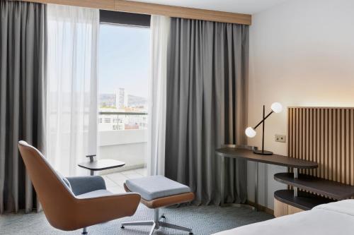 a hotel room with a bed and a desk and a chair at Courtyard by Marriott Biel Bienne in Biel