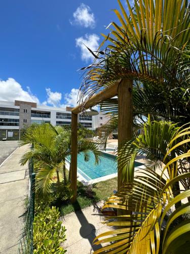 a swimming pool with palm trees and a building at casamarfrances in Praia do Frances