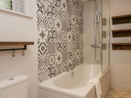 La salle de bains blanche est pourvue d'une baignoire et d'une douche. dans l'établissement The Bothy, à Keswick