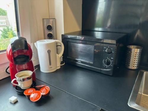 a kitchen counter with a microwave and some cut up tomatoes at T3 Horizon- Face Gare -18 Min Paris in Villemomble
