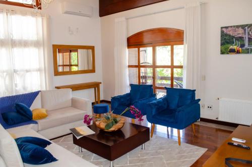 ein Wohnzimmer mit einem weißen Sofa und blauen Stühlen in der Unterkunft Suítes Casa Aurora in Canela