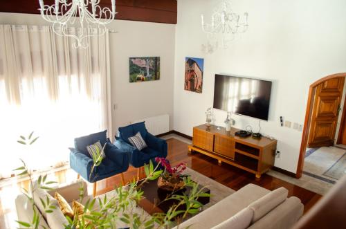 a living room with a couch and a television at Suítes Casa Aurora in Canela