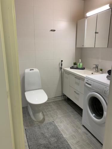 a bathroom with a toilet and a washing machine at StarHomes Studio Apartments in Oulu