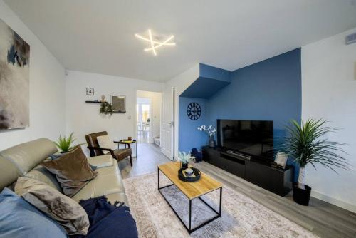 a living room with a couch and a tv at 3 Bedroom House near Milton Keynes Bowl, Sleeps 6, with Free Wi-Fi, Full Kitchen, Garden and Free Parking - 1BYC in Bedford
