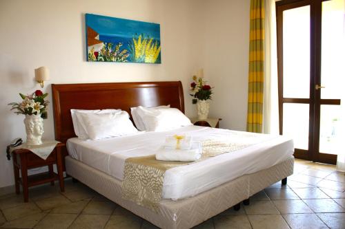 sypialnia z dużym łóżkiem z drewnianym zagłówkiem w obiekcie Grand Hotel Selinunte w mieście Marinella di Selinunte