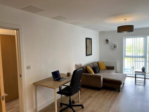 a living room with a couch and a desk with a laptop at Modern 1 Bedroom Serviced Apartment - Near City Centre in Doncaster
