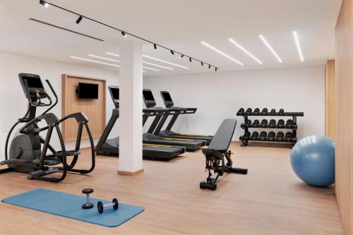 - une salle de sport avec des tapis roulants elliptiques et un ballon d'exercice bleu dans l'établissement Courtyard by Marriott Biel Bienne, à Biel