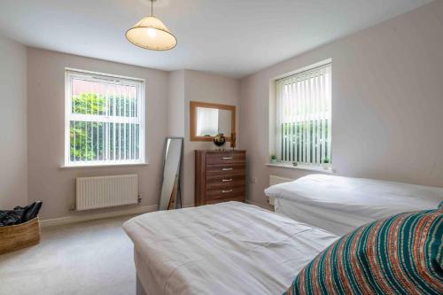 a bedroom with two beds and a dresser and two windows at Spacious Apartment Near Birmingham Centre and NeC in Birmingham