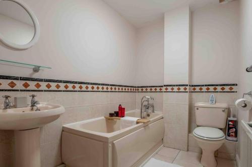 W łazience znajduje się umywalka, toaleta i lustro. w obiekcie Spacious Apartment Near Birmingham Centre and NeC w Birmingham