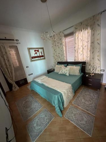 a bedroom with a bed and two rugs at Villa Mile in Berat