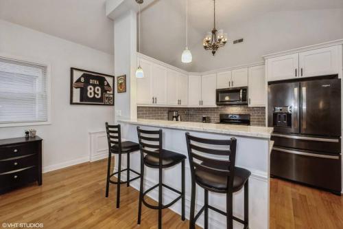 a kitchen with white cabinets and black bar stools at 2-Bed 2-Bath Apt - Close to UC w/ Free Parking in Chicago