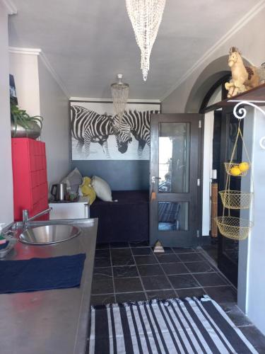 a kitchen with zebra paintings on the wall and a sink at Whale Rock Guest House in Plettenberg Bay