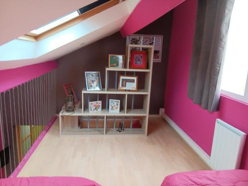 Habitación con paredes rosas y estante para libros. en LA BARAQUE, 