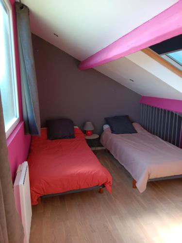 two beds in a room with pink and purple walls at LA BARAQUE 